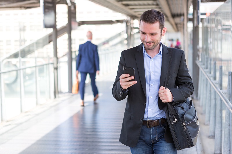 young businessman walking through airport using phone